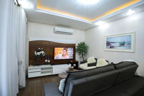 a living room with a couch and a flat screen tv at Casa Petri Gramado in Gramado