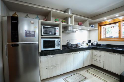 a kitchen with a stainless steel refrigerator and microwave at Casa Petri Gramado in Gramado