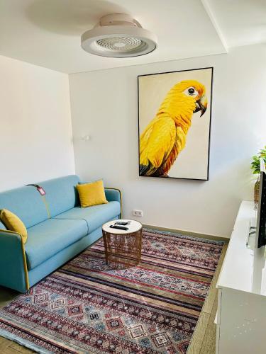 a living room with a blue couch and a picture of a yellow bird at AMBER APARTMENTS - SUNNY STUDIO in Morro del Jable