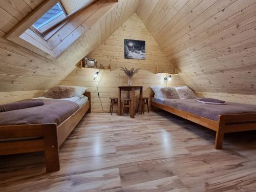 a attic room with two beds and a table at Domki u Jacka z sauną widok na Kasprowy in Ząb