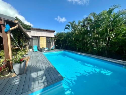a swimming pool with a wooden deck next to a house at Villa Saphir B & B in Sainte-Anne