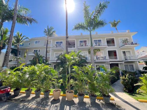 Un gran edificio blanco con palmeras delante. en Nice condo with fresh pool, en Punta Cana