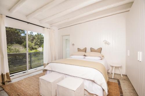 a white bedroom with a bed and a large window at Posada Arenas in José Ignacio