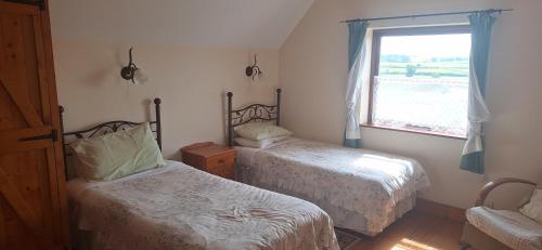 ein Schlafzimmer mit zwei Betten und einem Fenster in der Unterkunft Cottage by the sea in Enniscrone