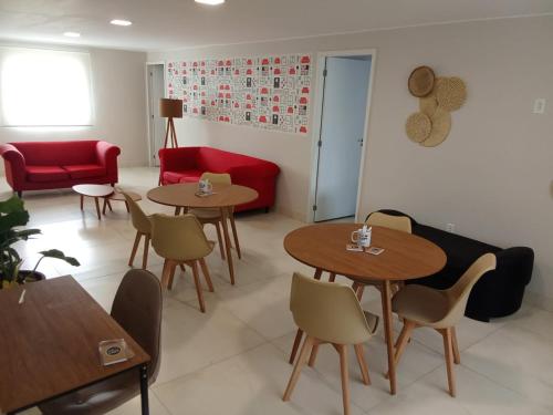 Una sala de estar con mesas y un sofá rojo. en Hospedagem e Coworking - suítes, en Anápolis