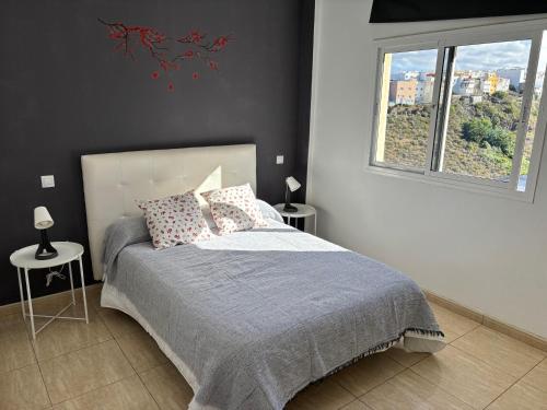 1 dormitorio con 1 cama con 2 mesas y una ventana en Arucas Relax, en Arucas