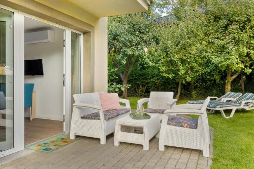 a patio with white wicker chairs and a table at Villa LILIA in Międzywodzie