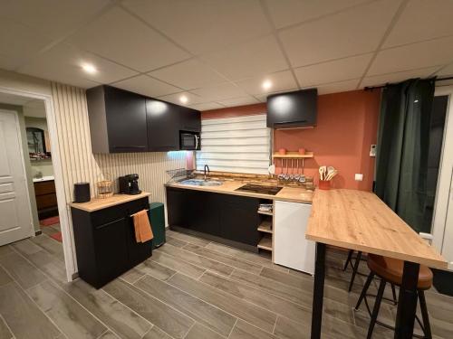 cocina con armarios negros y mesa de madera en chez isabelle et thierry, en Harnes