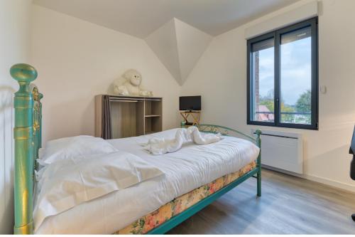 a bedroom with a bed with white sheets and a window at Le Hameau Paisible in Butot