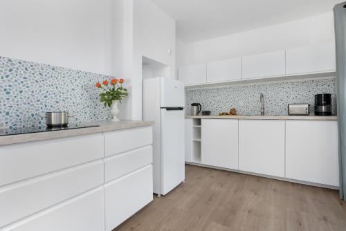 a kitchen with white cabinets and a white refrigerator at Villa LILIA in Międzywodzie