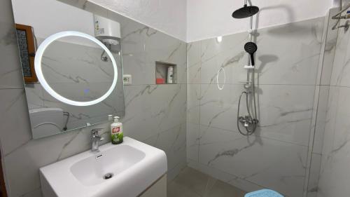 a white bathroom with a sink and a mirror at Priam Garden in Durrës
