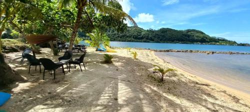 a group of chairs sitting on a sandy beach at Le Neliza Beach Lodge Raiatea in Opoa