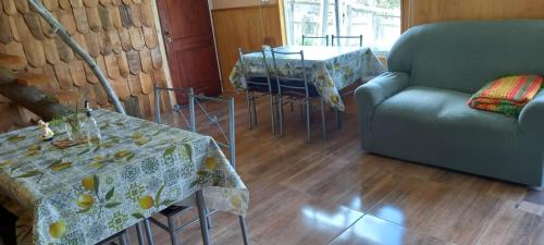una sala de estar con un sofá, una mesa y sillas en Cabaña el Sauco, en Puerto Guadal