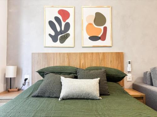 a bedroom with a green bed with two pictures on the wall at Estúdio na melhor rua do Leblon in Rio de Janeiro