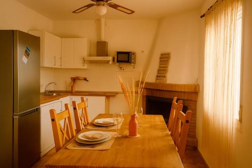 a kitchen with a wooden table with chairs and a refrigerator at Casa del Agua - Escapada rural con chimenea y vistas a Sierra Nevada in Abrucena