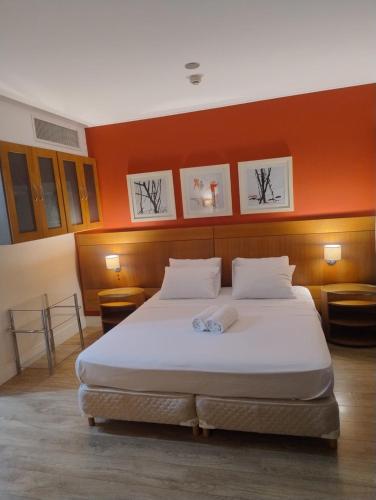 a large bed in a room with an orange wall at Hotel Slaviero Grandflats Suíte Master Luxo in Sao Paulo