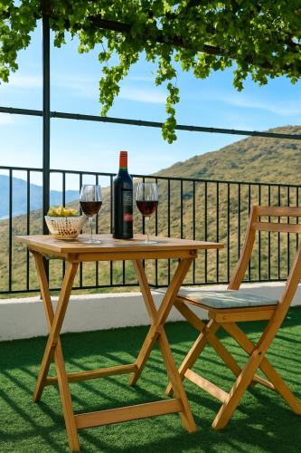 a wooden table with two glasses of wine and a chair at Casa del Agua- Casa rural con encanto en Sierra Nevada terraza y chimenea in Abrucena