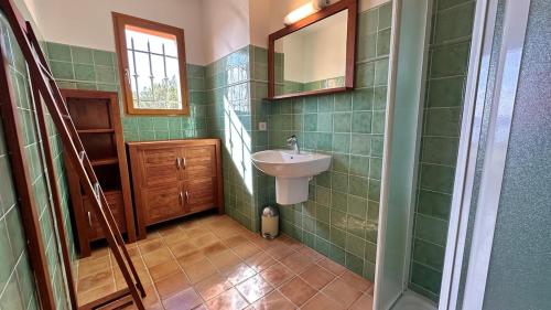 un bagno piastrellato verde con lavandino e specchio di La Castagna Sea View Pool Villa a Coti-Chiavari