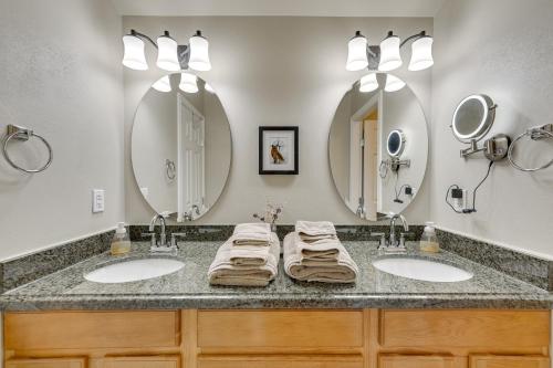 a bathroom with two sinks and two mirrors at Stunning Alaskan Getaway with River and Mtn Views in Eagle River