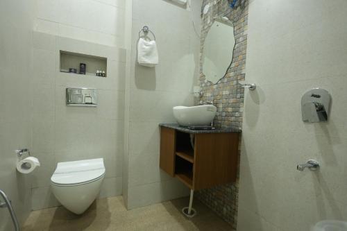 a bathroom with a toilet and a sink and a mirror at Roots & Peaks in Rishīkesh