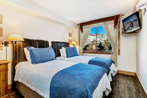 twee bedden in een kamer met een tv en een raam bij Antlers at Vail Resort in Vail