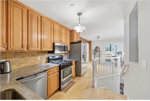 a kitchen with wooden cabinets and stainless steel appliances at designer abode condo min to Manhattan in jersey city in Jersey City