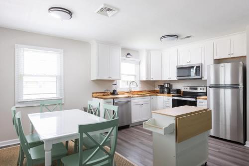 - une cuisine avec des placards blancs, une table et un réfrigérateur dans l'établissement Newly Updated Cottage in the Heart of KDH, à Kill Devil Hills