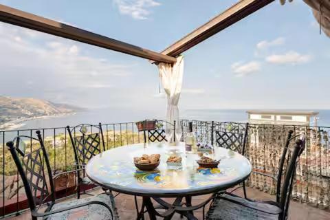 een tafel op een balkon met uitzicht op de oceaan bij DIMORA DISIU - Jacuzzi & Sea View - 4 minuti a piedi dal centro in Taormina