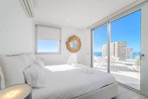a white bedroom with a bed and a large window at White Haven in Adeje