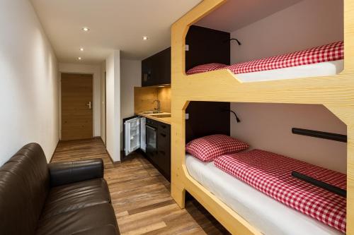 two bunk beds in a small room with a couch at TinyAlps in Saalbach Hinterglemm