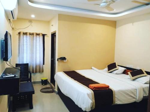 The Royal Inn 1 في فيساخاباتنام: غرفة نوم بها سرير ومكتب وتلفزيون