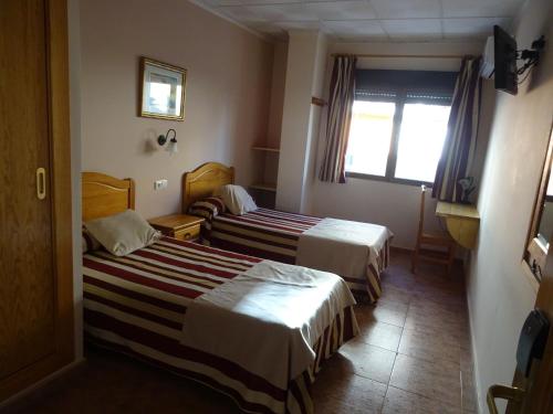 Una habitación de hotel con dos camas y una ventana. en Hotel Mesón el Castillo, en Bañeres de Mariola