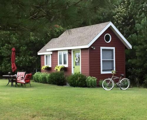 Una casa roja con una mesa y una bicicleta en el patio. en Serene Tiny House with a Big Charm for Glamping in Virginia, en Accomac