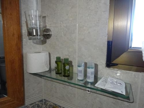 una estantería de cristal en un baño con botellas. en Hotel Mesón el Castillo, en Bañeres de Mariola