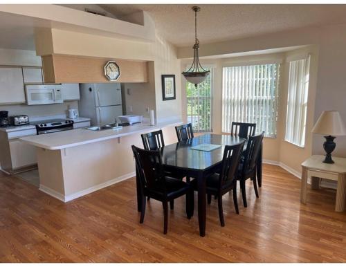 Cozy and Spacious Apartment near Disney Kissimmee في كيسيمي: مطبخ وغرفة طعام مع طاولة وكراسي