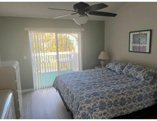 Cozy and Spacious Apartment near Disney Kissimmee في كيسيمي: غرفة نوم بها سرير ومروحة سقف