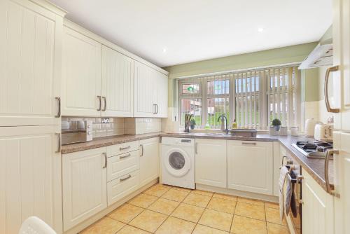 une cuisine avec des armoires blanches et une laveuse et une sécheuse dans l'établissement Spacious 4 Bedroom House with Parking, à Lamesley