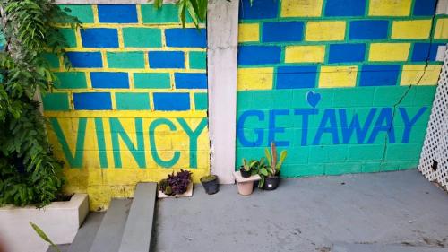a building with a colorful wall with plants and graffiti at 5 mins walk from Kingstown! - McKies Hill Suite #1 - Your Home Away from Home in Kingstown