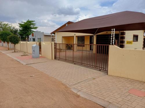 a fence in front of a house with a building at Watergat guest house in Rehoboth