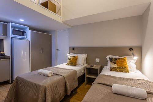 ein Hotelzimmer mit 2 Betten und einem Kühlschrank in der Unterkunft Injoy Lofts & Studios Ipanema in Rio de Janeiro