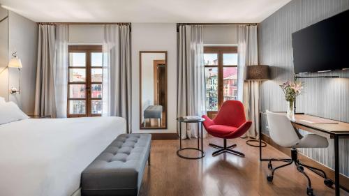 a hotel room with a bed and a desk and a red chair at NH Collection León Plaza Mayor in León