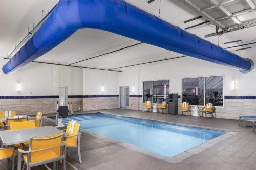 a large pool with chairs and a table and a blue slide at GLō Best Western Dawley Farms In Sioux Falls in Sioux Falls
