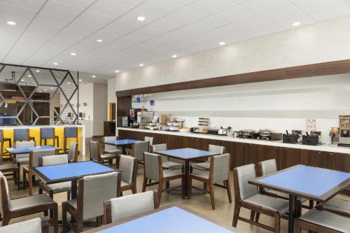 a restaurant with tables and chairs and a counter at GLō Best Western Dawley Farms In Sioux Falls in Sioux Falls