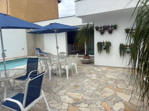 a patio with a table and chairs and a pool at Casa Espaçosa com 5 Quartos Piscina Privativa 300m da Praia Ar condicionado em todos cômodos in São Sebastião