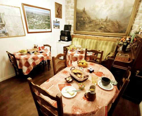 a dining room with two tables and chairs with food on it at A la Grenouille du Jura in Bellignat