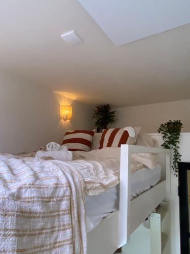 ein Schlafzimmer mit einem weißen Bett mit gestreiften Kissen in der Unterkunft Cosy beach cottage in Zandvoort