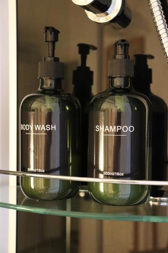 two bottles of soap on a glass shelf in front of a mirror at Hostel Bertha-Marie Flamingo Lounge in Greifswald