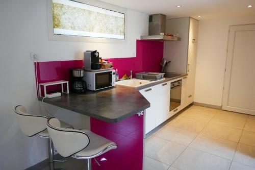 a kitchen with pink walls and a counter and chairs at Escapade Champêtre in Chevaigné