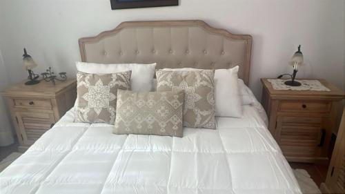 1 dormitorio con 1 cama blanca con almohadas y 2 mesitas de noche en Casa Clemente en La Bombilla, en Los Llanos de Aridane