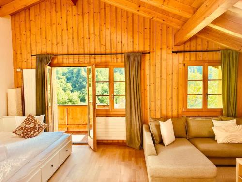 a bedroom with a bed and a couch and windows at Chalet with Scenic Valley & Mountain Views in Lütschental